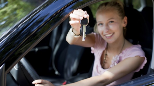 Junge Frau zeigt ihren Schlüssel aus dem Auto heraus