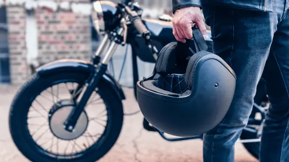 Mann hält schwarzen Motorradhelm in der Hand