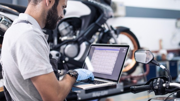 Mechaniker untersucht Daten eines Motorrads mit einem Laptop