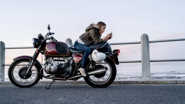 Junge Frau sitzt verkehrtherum auf einem Motorrad