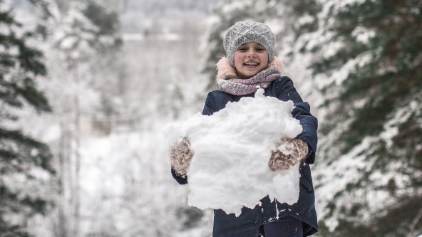 Kind hält großen Haufen Schnee in den Händen