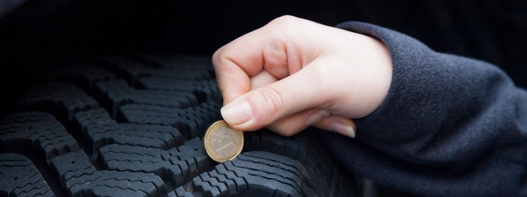 Frau misst das Reifenprofil mit einer Euromünze
