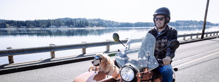 Mann sitzt mit Hund in einem Zweisitzer-Motorrad