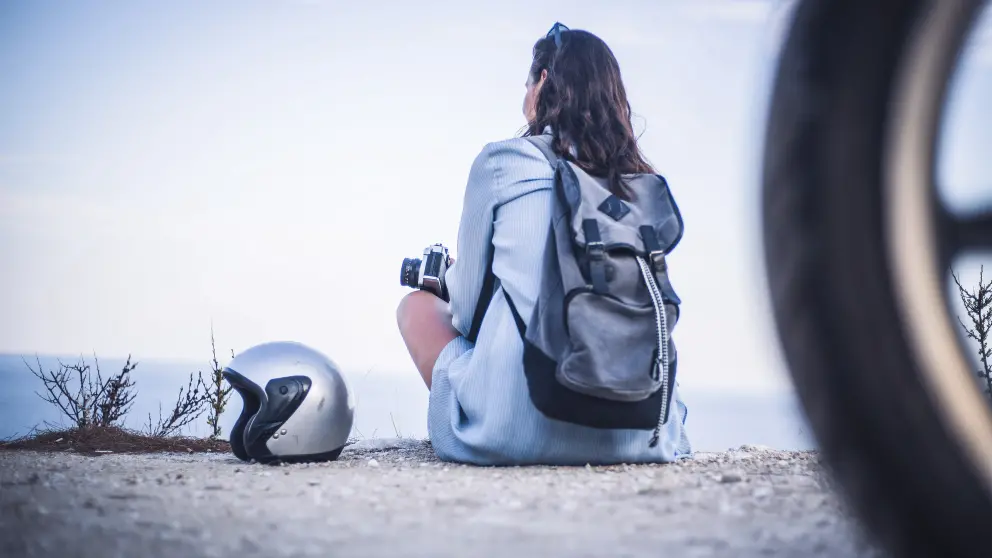 Frau sitzt auf einer Straße und neben ihr liegt ein Motorradhelm