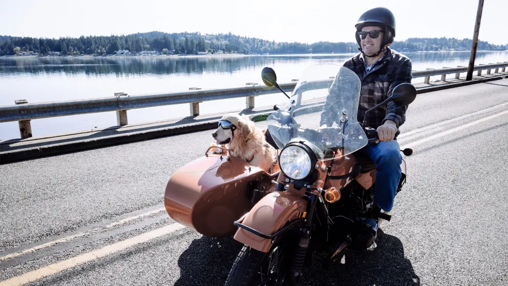 Mann sitzt mit Hund in einem Zweisitzer-Motorrad