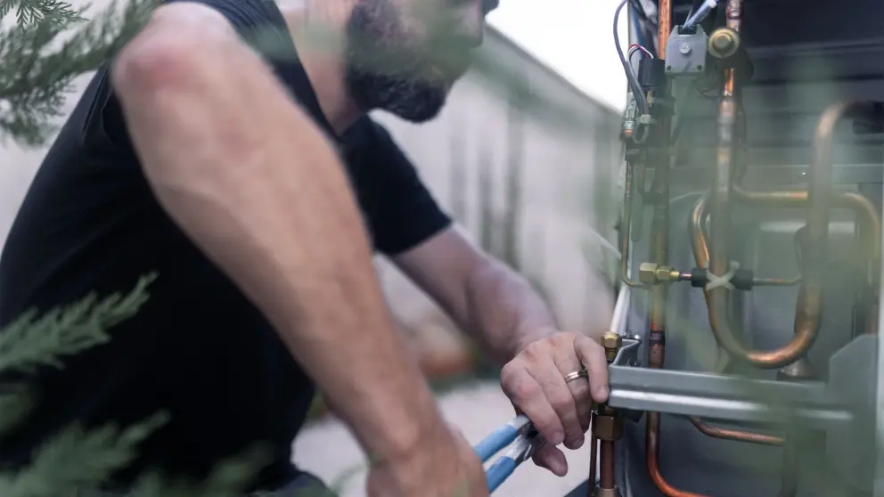 Handwerker arbeitet mit Zange an Wärmepumpe